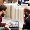 Business partners meet with people on videocall in hotel lobby, attending online teleconference chat to share project ideas, travelling for work. Entrepreneurs working with videoconference.