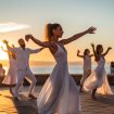 A group of people doing a dance on the beach.