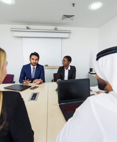 Mixed business team in Dubai. Business meeting with men wearing kandura and western people in the office