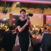 A shallow focus of a young cameraman filming a wedding celebration in a restaurant